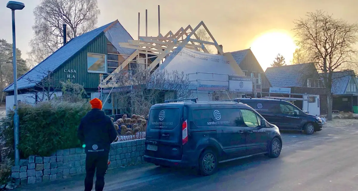 En frostig vintermorgon vid ett takbygge där nya takstolar reser sig över huset och Sands bilar står parkerade på gatan